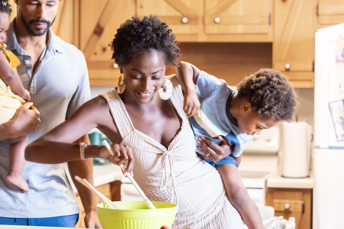 Parents cooking together in a bright kitchen while their children look on